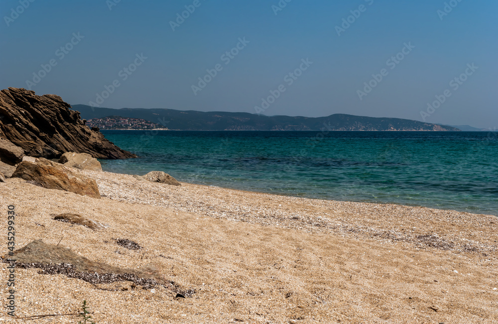 Part of Wild Beach in Harbour of Singitic Gulf in Aegean Sea with Pyrgadikia Village on Hill Under Blue Sky - Sea Landscape Sight from Coastline on Sithonia Chalkidiki Greece