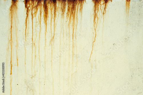 Dark orange streaks on a pale yellow plaster wall