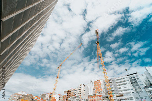 Bunch of yellow cranes on the city under a bright and blue sky with copy space