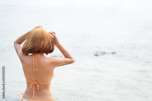 A woman in a bikini turns her back on the sea © njmucc