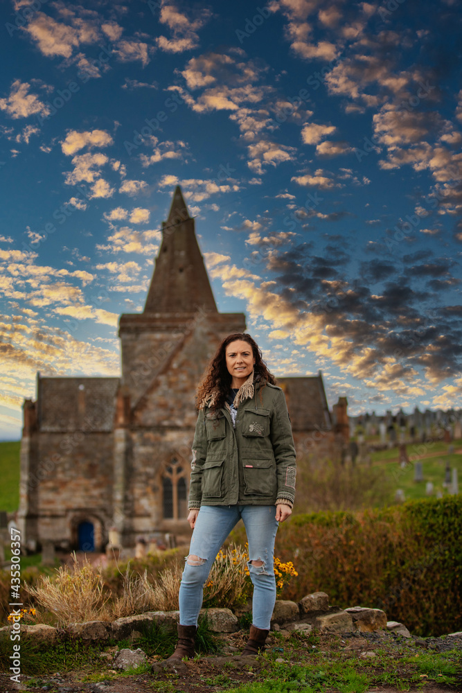 Model standing in front of The Auld Kirk in St Monans at sunset