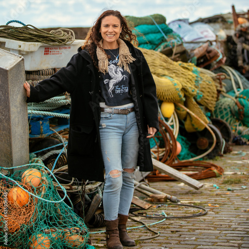 Woman in duffle coat  standing among fishing nets