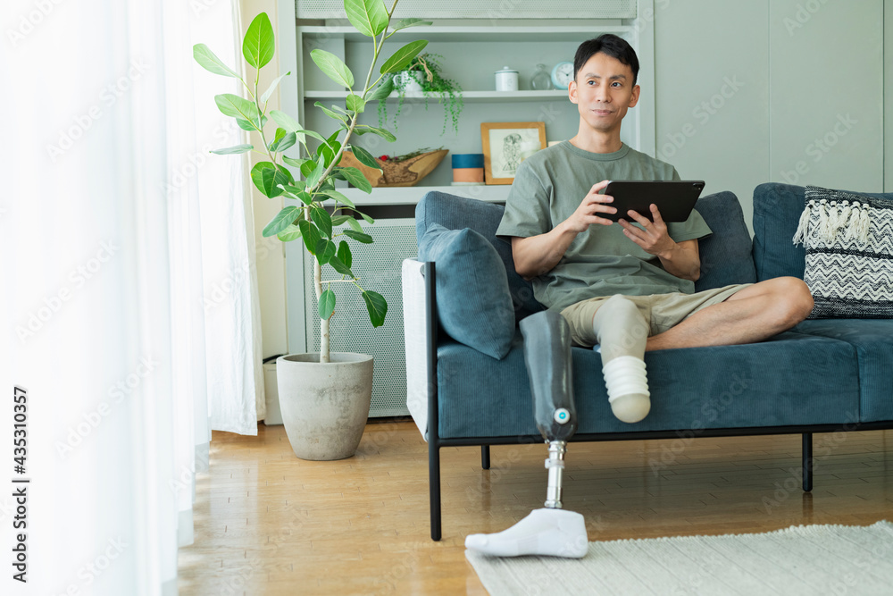 ソファでくつろぐ義足の男性 ソファでくつろぐ義足の男性