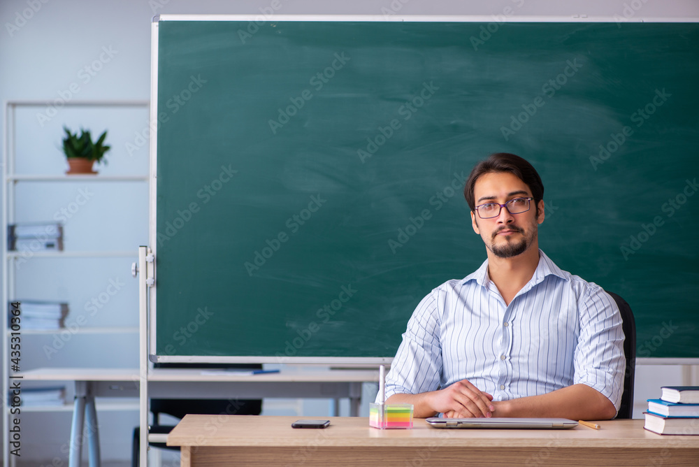 Young male teacher in front of blackboard Young male teacher in front of blackboard