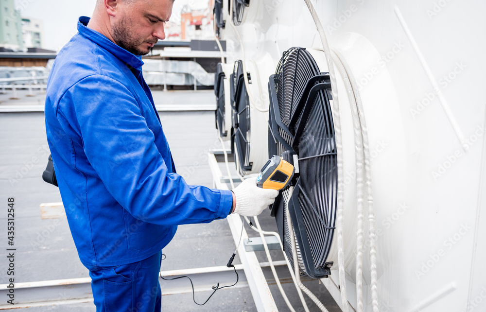 Technician uses a thermal imaging infrared thermometer to check the condensing unit heat exchanger. Technician uses a thermal imaging infrared thermometer to check the condensing unit heat exchanger.