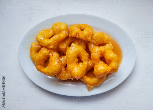 Obraz na płótnie Picarones, Peruvian Dessert made from Squash and Sweet Potato and Served in a Doughnut Form with Syrup made from Panela on a White Table w salonie