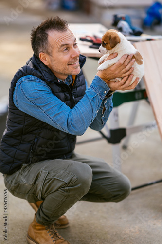 a man holding his little puppy Jack Russell in his arms