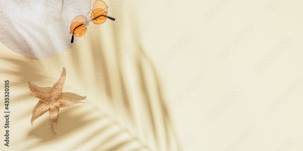 Summer minimal background with sunhat, colored sunglasses, starfish on sandy color background with daylight shadows Summer minimal background with sunhat, colored sunglasses, starfish on sandy color background with daylight shadows