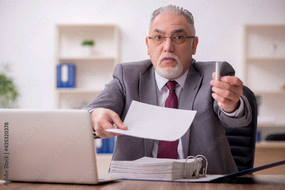 Old male employee working in the office Old male employee working in the office