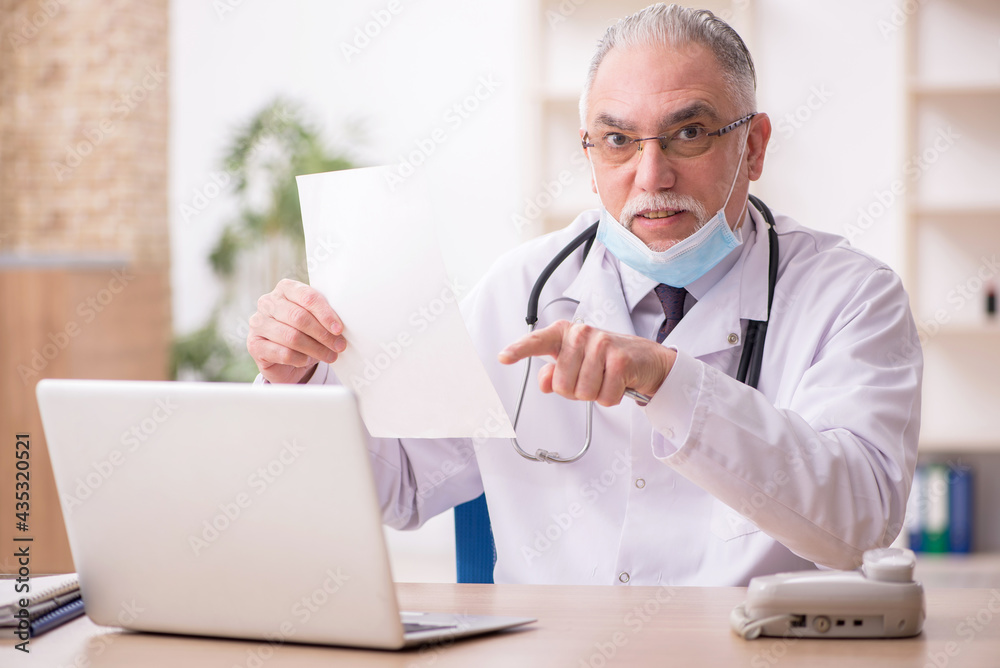 Old male doctor working in the clinic during pandemic Old male doctor working in the clinic during pandemic