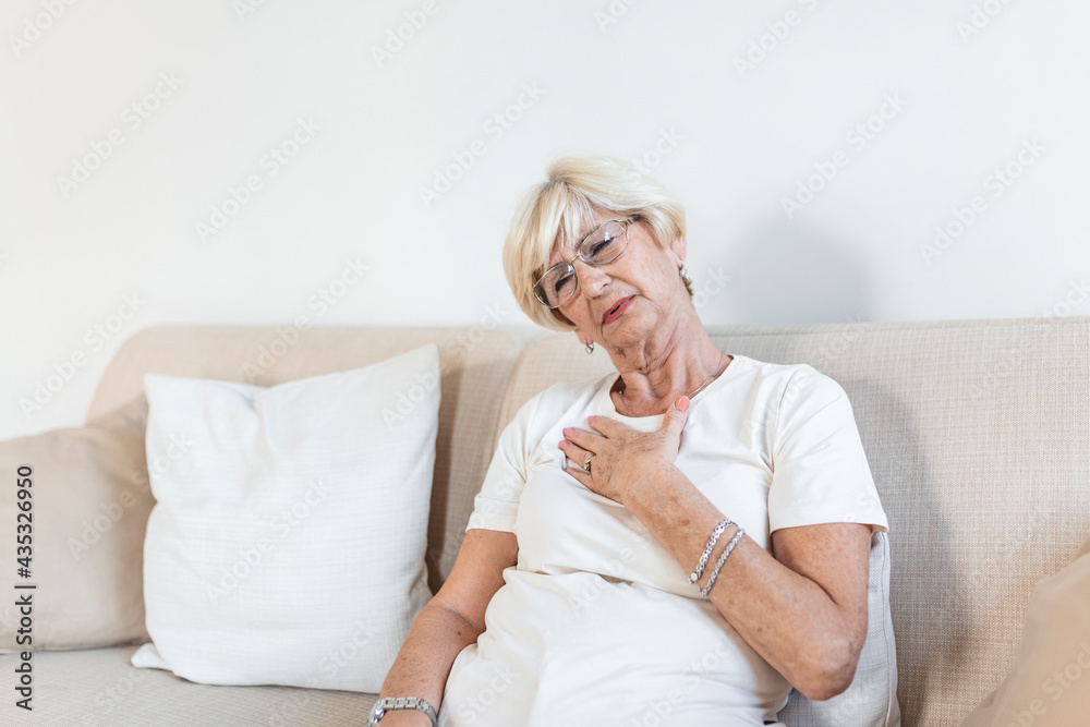 Senior woman having a pain in the heart area. Heart Attack. Chest pain. Health Care, Medical Concept. Elderly Woman having heart attack at home Senior woman having a pain in the heart area. Heart Attack. Chest pain. Health Care, Medical Concept. Elderly Woman having heart attack at home