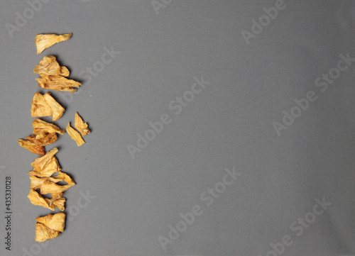 Healthy eating concept - dried pineapple isolated on gray background flat lay photo