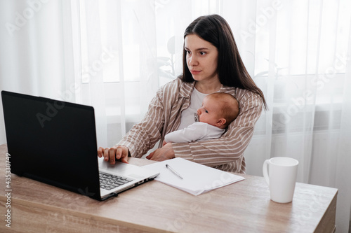 Working. breastfeeding woman with infant near laptop. © ninelutsk