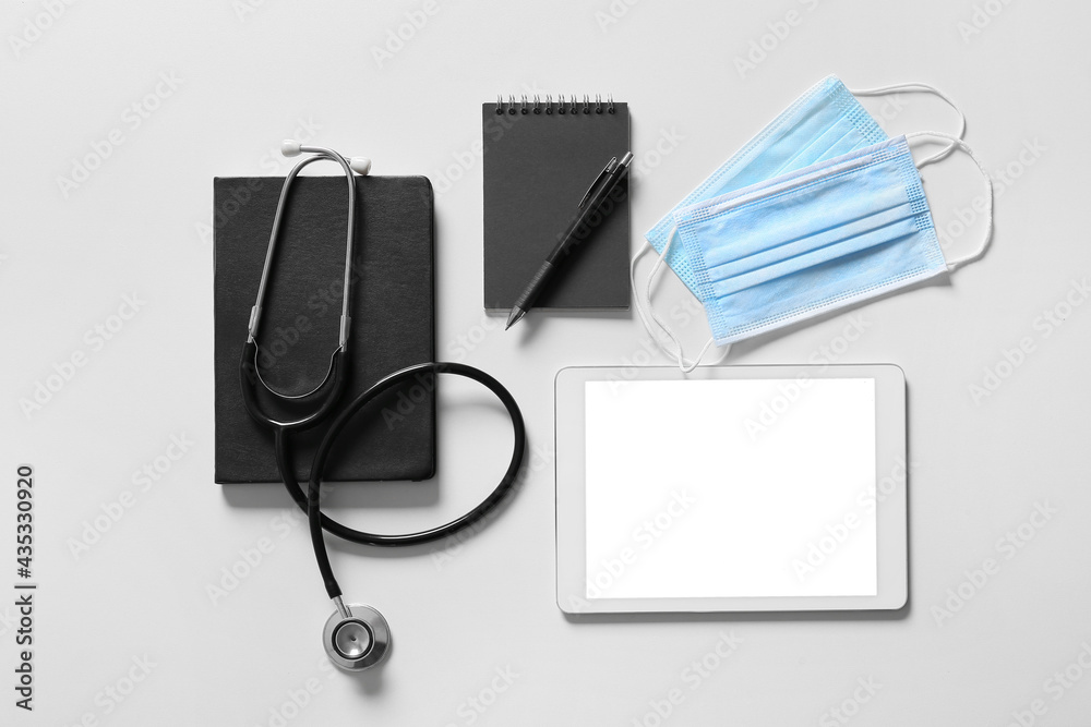 Composition with modern stethoscope and tablet computer on light background Composition with modern stethoscope and tablet computer on light background