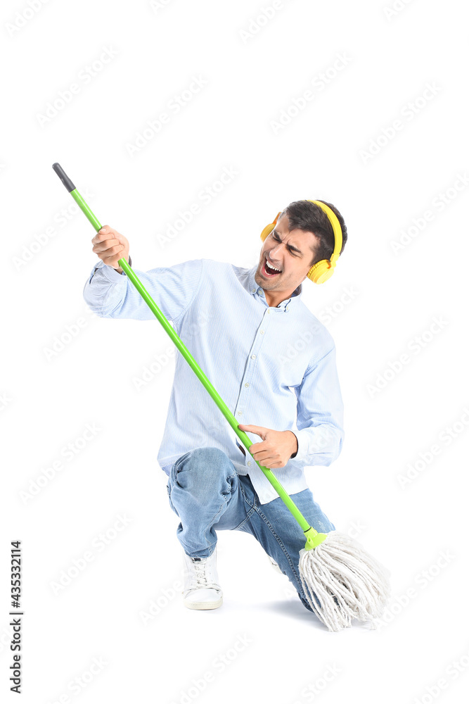 Young man in headphones with floor mop on white background Young man in headphones with floor mop on white background