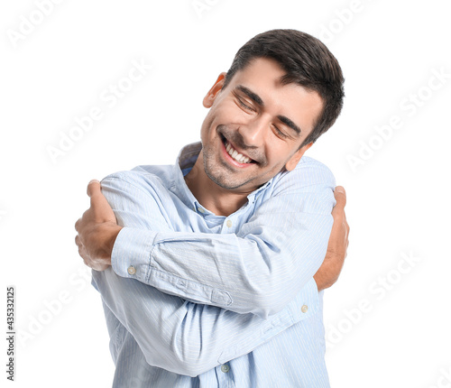 Young man hugging himself o...