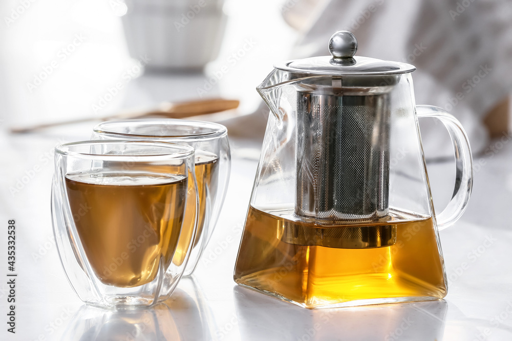 Teapot and glasses with hot tea on table in kitchen Teapot and glasses with hot tea on table in kitchen