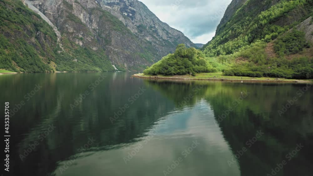A magnificent view of the Naeroyfjord - one of the most beautiful fjords in Norway. Forest-covered mountains tower above the narrow waterway and are reflected in mirror-like still waters. A magnificent view of the Naeroyfjord - one of the most beautiful fjords in Norway. Forest-covered mountains tower above the narrow waterway and are reflected in mirror-like still waters.