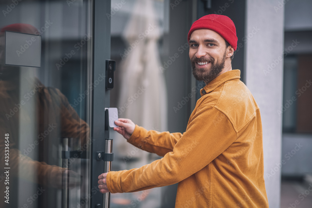 Bearded young man opening the door with an access card