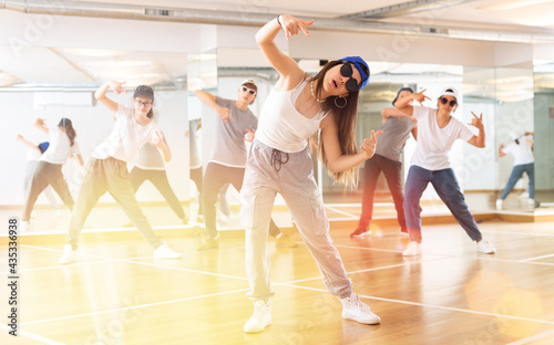 Happy smiling teenagers practicing vigorous hip hop movements in dance class