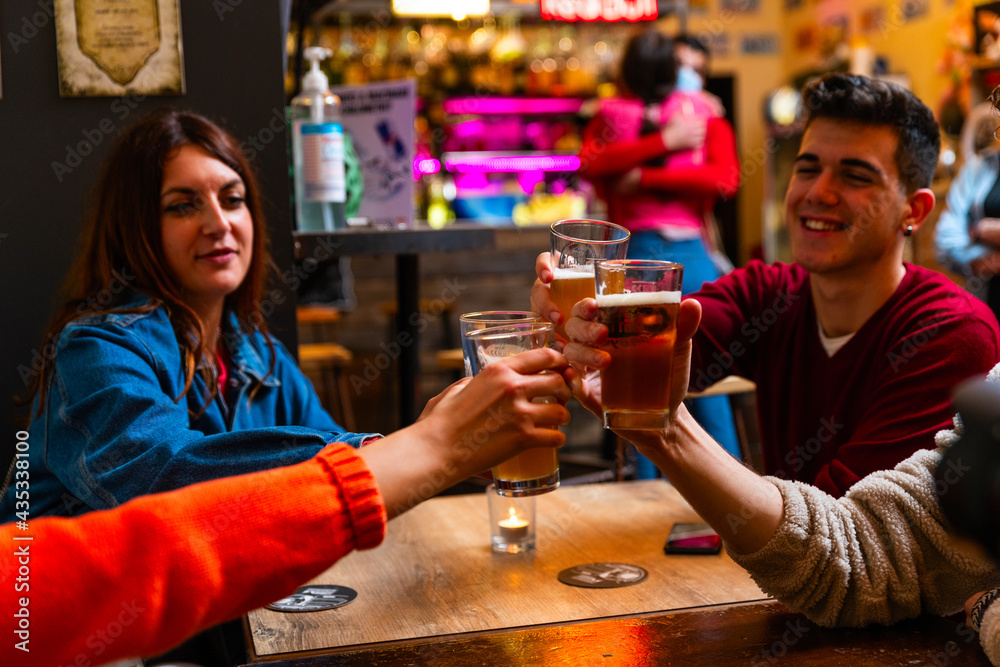 Young people drink a toast with beer in a pub.