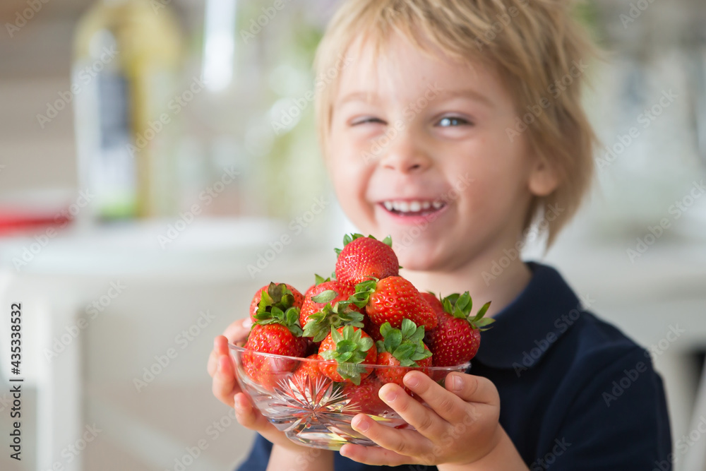 Blond toddler child, holding a bowl with strawberries, focus on the strawberries Blond toddler child, holding a bowl with strawberries, focus on the strawberries