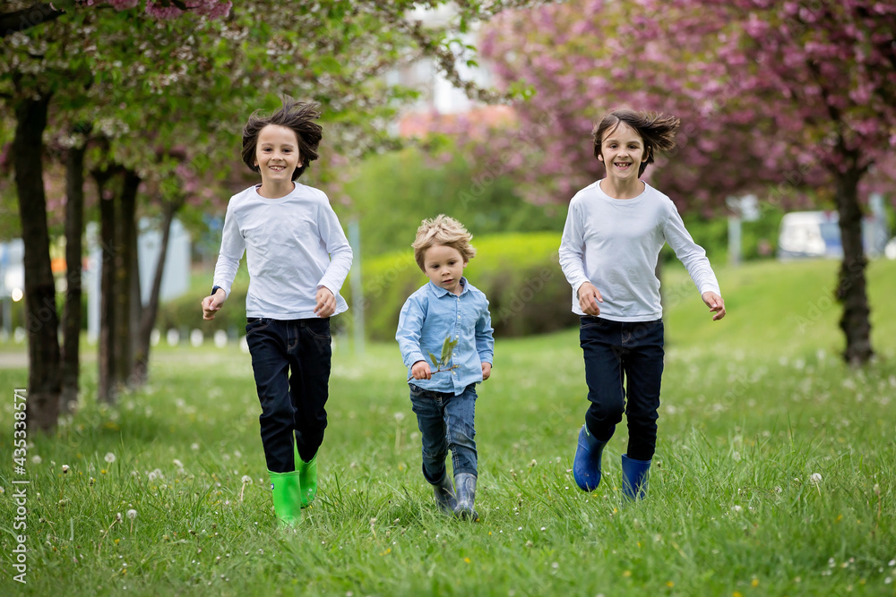 Happy children of different age groups, running together in the park, springtime, having fun Happy children of different age groups, running together in the park, springtime, having fun