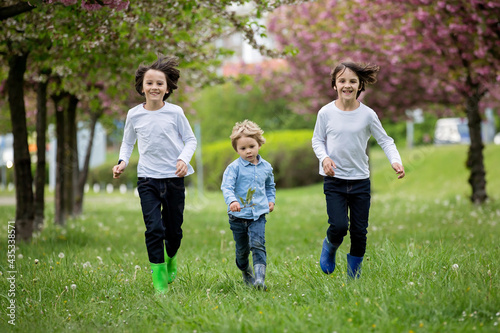 Happy children of different age groups, running together in the park, springtime, having fun