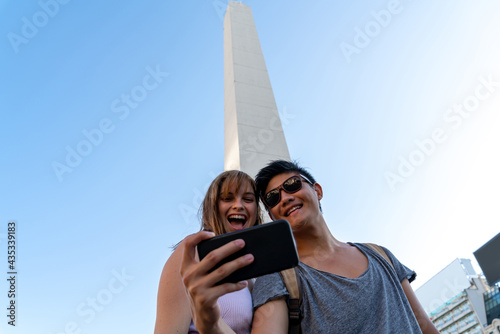 Young couple taking selfies at an attraction of a big city