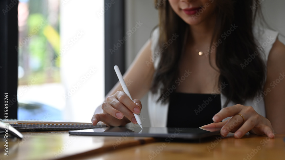 Cropped shot of young businesswoman using stylus pen writing on digital table while sitting in cafe. Cropped shot of young businesswoman using stylus pen writing on digital table while sitting in cafe.