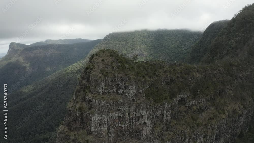 4K drone shot slowly orbiting a big mountain cliff at Border Ranges National Park, New South Wales Australia. Drone spins and zoom out above beautiful texture in nature on a cloudy day. 4K drone shot slowly orbiting a big mountain cliff at Border Ranges National Park, New South Wales Australia. Drone spins and zoom out above beautiful texture in nature on a cloudy day.