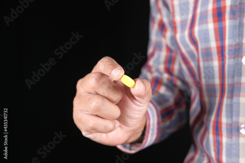 young man hand holding medical pills isolated on black 