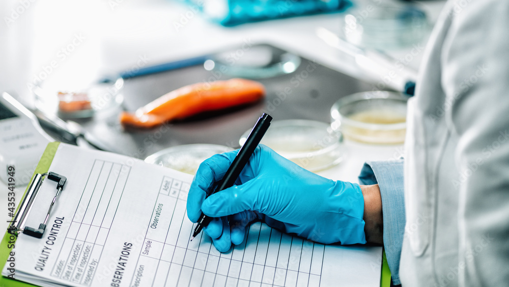 Food Safety and Quality Management. Inspector Filling Out Quality Control Form in a Laboratory Food Safety and Quality Management. Inspector Filling Out Quality Control Form in a Laboratory