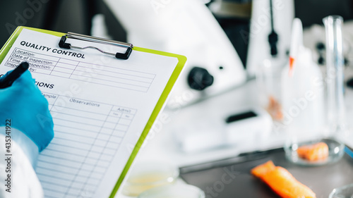 Food Safety and Quality Management. Inspector Filling Out Quality Control Form in a Laboratory photo