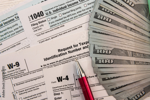 1040 tax form with pen and US dollar bills