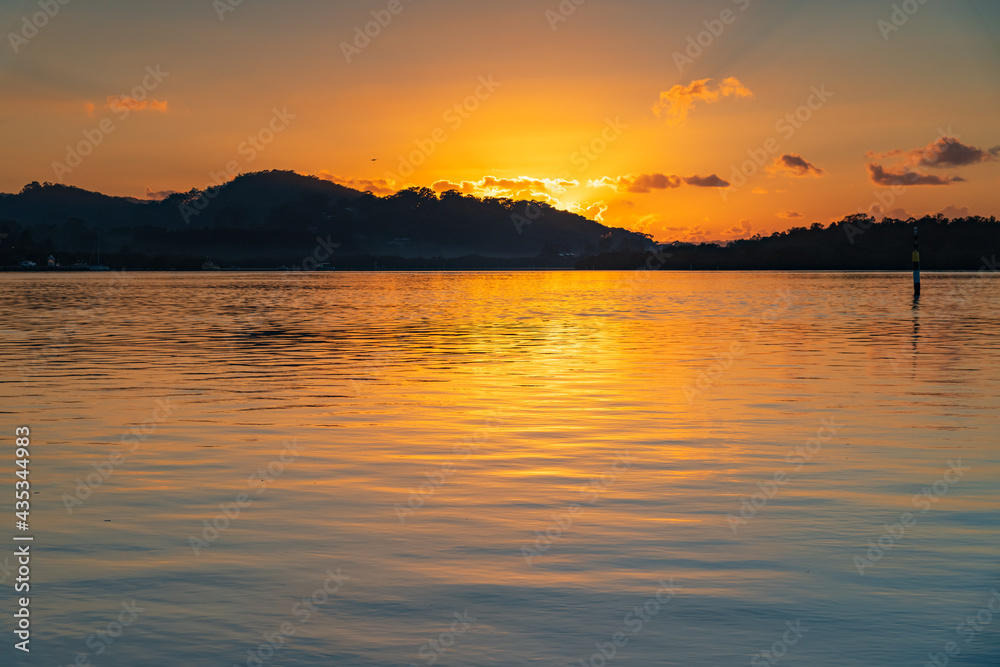 Sunrise waterscape with scattered clouds and yellow highlights