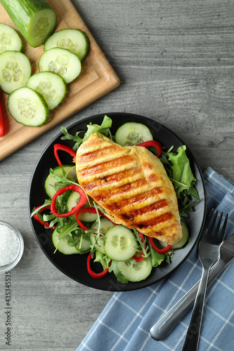 Salad with grilled chicken on gray textured table