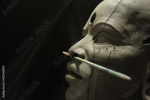 Portrait of indigenous woman. Statue in process of creation with body modifications. Profile face with ample space for text on black background. photo