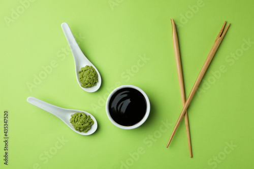 Wasabi, soy sauce, and chopsticks on green background