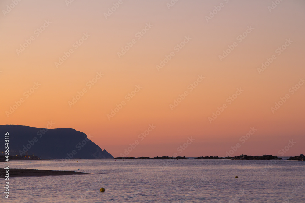 Beautiful sunset on the shores of the Atlantic Ocean overlooking Mount Conero, Marche, Italy, Europe.