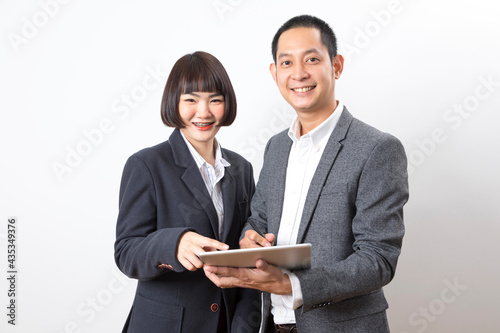 Businessman and woman holding tablet while discussing marketing plan standing on white background.