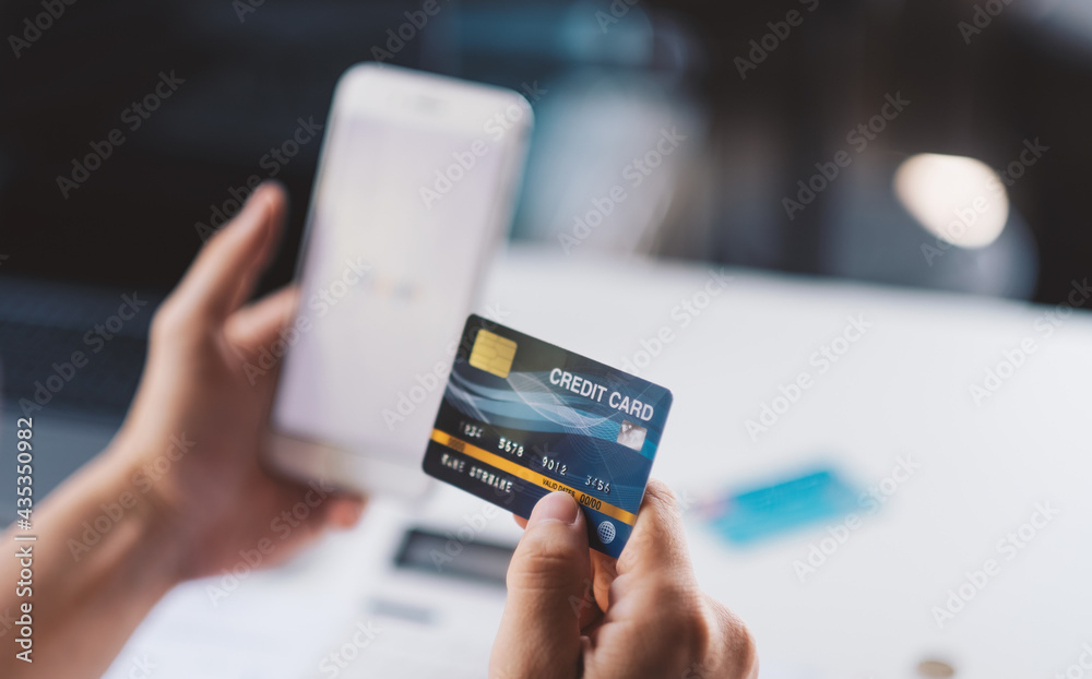 Close up hand holding credit card and modern smartphone, enjoying purchasing goods in internet store using mobile phone application, online shopping