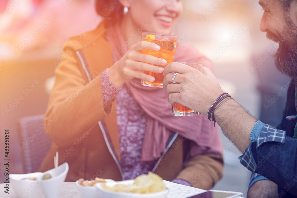 Happy loving couple enjoying in outdoor bar cafe,restaurant.Love,dating,food,lifestyle.Boyfriend and girlfriend sitting in a bar,drinking spritz aperitif,making a toast in an historical centre Happy loving couple enjoying in outdoor bar cafe,restaurant.Love,dating,food,lifestyle.Boyfriend and girlfriend sitting in a bar,drinking spritz aperitif,making a toast in an historical centre