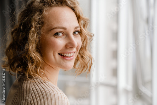 Young blonde woman smiling and looking at camera indoors