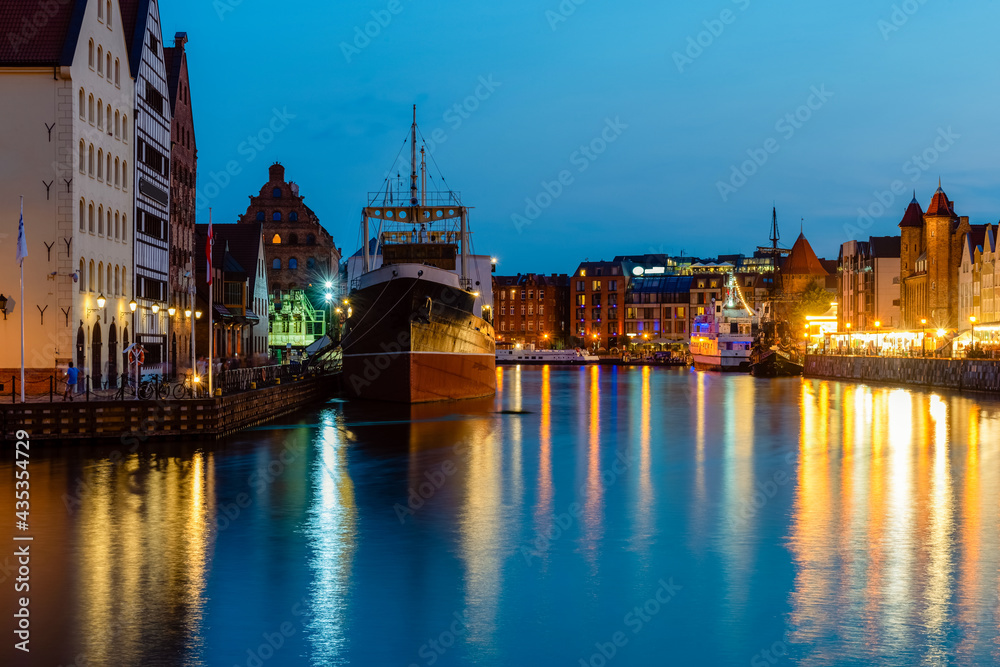 Gdansk night city riverside view with moored ship. View on famous facades of old medieval houses