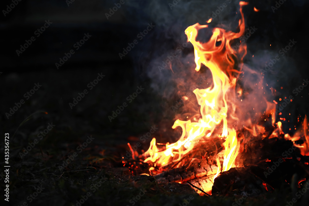 Burning red hot sparks fly from big fire. Burning coals, flaming particles flying off against black background. Burning red hot sparks fly from big fire. Burning coals, flaming particles flying off against black background.