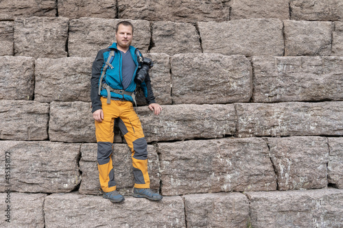 A man standing on granit big blocks stone wall.