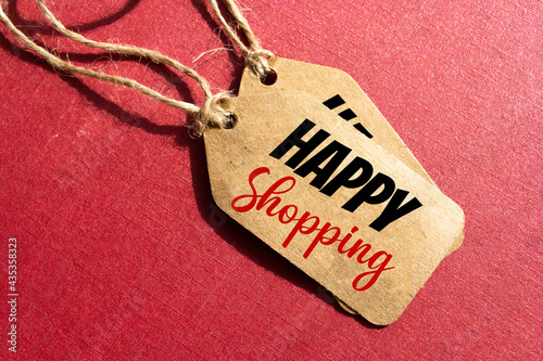 Brown tag on red background. Top view, copy space. Hang tag with text "Happy shopping"