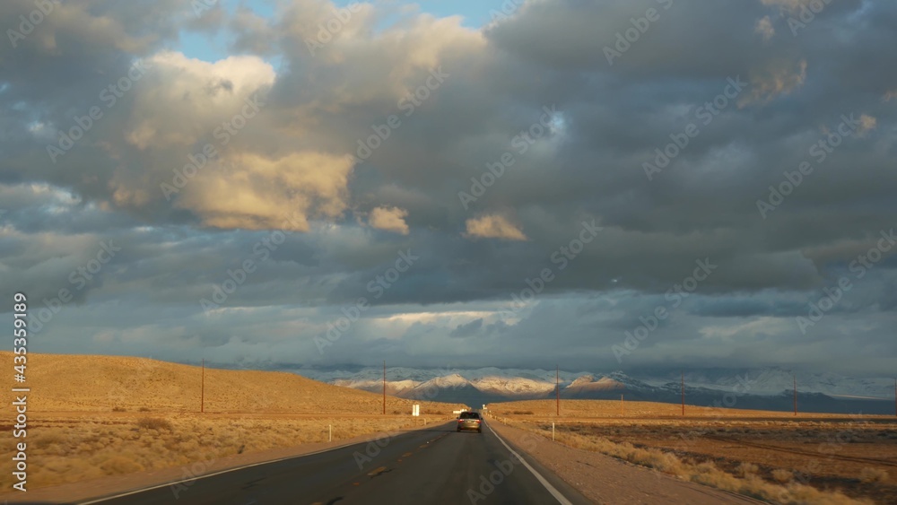 Road trip, driving auto from Death Valley to Las Vegas, Nevada USA. Hitchhiking traveling in America. Highway journey, dramatic atmosphere, sunset mountain and Mojave desert wilderness. View from car.
