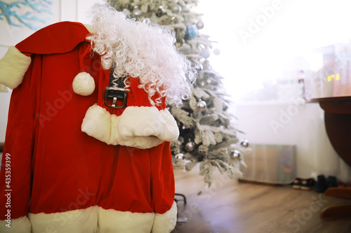 Santa costume hanging in white room. Chair with clothes from Santa Claus © alexkich
